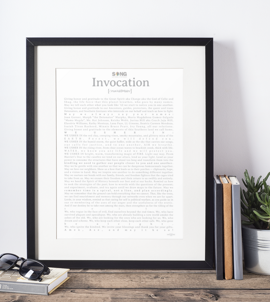 Framed print with text on a white wall with books and a plant below